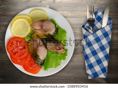 smoked mackerel on a plate. mackerel with lemon and tomato on a wooden background