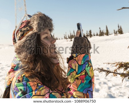 Young woman smiling with smart phone and winter landscape