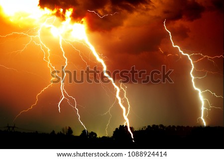 Lightning strike on the dark cloudy sky. Orange, yellow and red toned image.