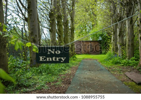 No entry sign hanging on a chain at the side of a pathway in the countryside at daytime