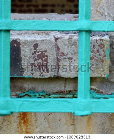 vertical teal iron bars againt brick