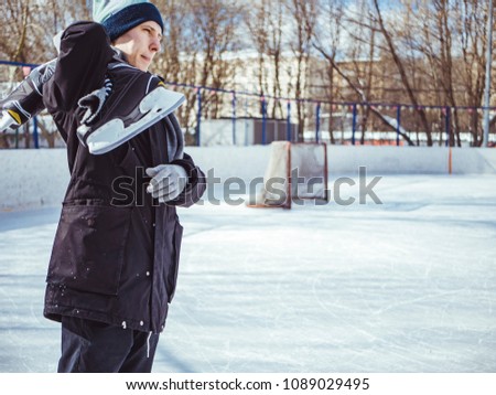 young man portrait holding skates on the rink on a winter day