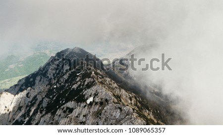 spring landscape with the mountain peaks covered with snow and clouds. aerial view by drone. romanian mountains