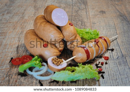 Fresh boiled Wiener sausages with green herbs and vegetables isolated on the white background.