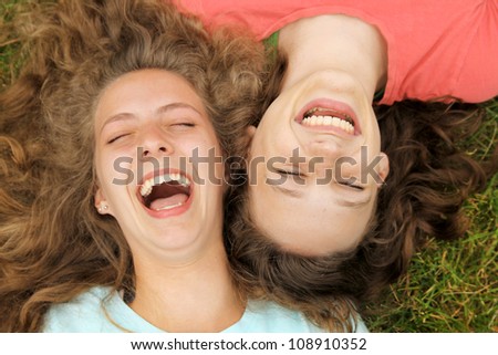 Happy teenagers friends lying on a grass laughing in a park Royalty-Free Stock Photo #108910352
