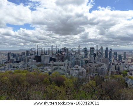 Aerial view of Montreal downtown from Mont Royal Belvedere Kondiaronk in the sunny spring weather. Green trees, Montreal downtown and Mount Saint-Hilaire on the horizon