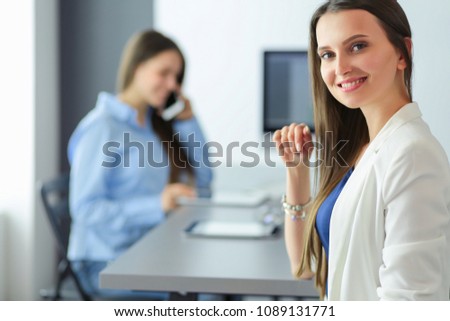 Two female colleagues in office sitting on the desk