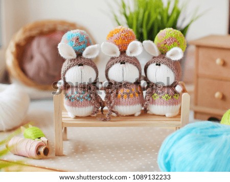 Handmade knitted toys. 3 knitted bunnies in colorful sweaters and hats with big pompoms. Easter gift card