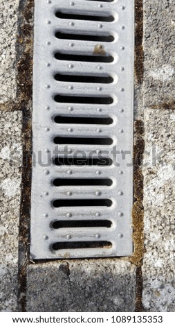 a gutter in a backyard is covered with a grating