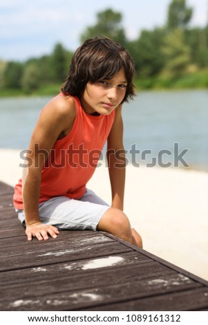 beautiful boy in an orange T-shirt resting on the beach