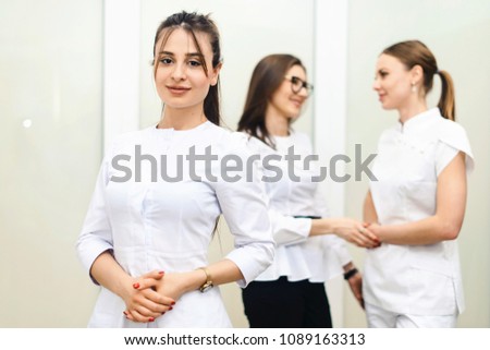 Cheerful group of young dentists and their assistants standing in the dental office and looking at camera and friendly smiling at white background of medical room.