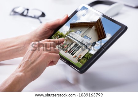 Close-up Of A Person's Hand Holding Digital Tablet With House On Screen
