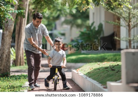 dad help his son learning to ride a bike using balance or push bikecycle Royalty-Free Stock Photo #1089178886