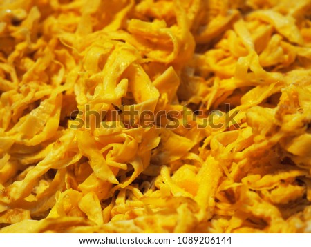 Macro close up pile of slice cut yellow golden deep fried Thai local traditional egg omelette string, dark shadow background, as ingredient for Rice mixed with Shrimp paste (Kao Kluk Kapi)