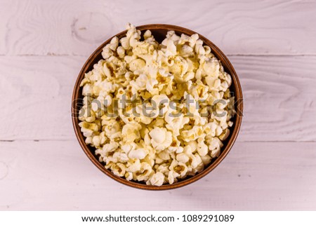 Ceramic bowl with popcorn on white wooden table. Top view