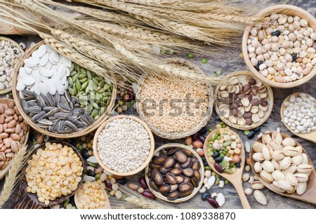 Collection of cereal grain seeds and beans in wooden equipment with dry wheat put on grunge wooden background