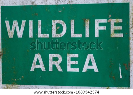 A weathered sign sayng wildlife area in white on a green background