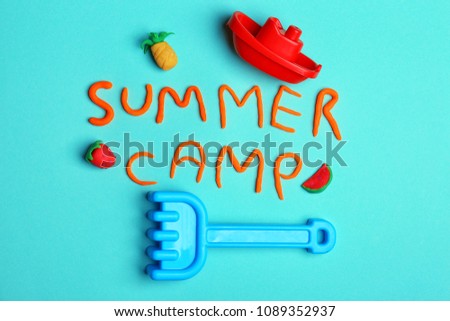 Flat lay composition with words SUMMER CAMP made from modelling clay and beach toys on color background