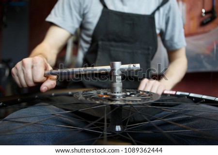 Photo of master repairing wheel of bicycle.