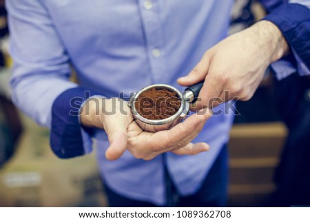 Picture of barista man with ground coffee in hands