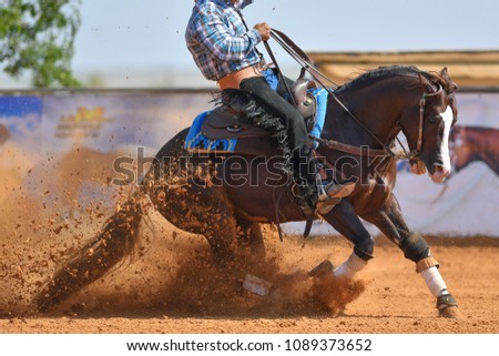 The side view of a rider sliding the horse in the sand.