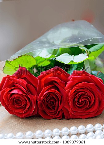 pictured in the photo composition from a bouquet of red roses and pearl beads