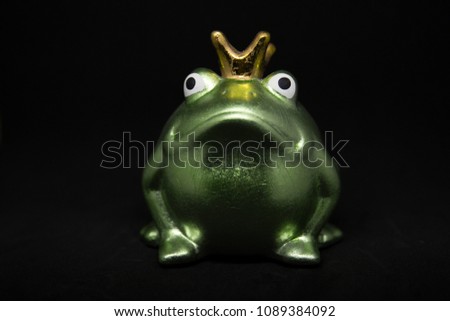 Depiction of the green frog prince with gold crown on a black background