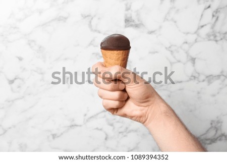 Man holding yummy ice cream on marble background. Focus on hand