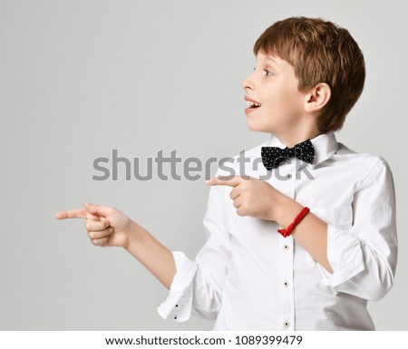 Young school boy in white shirt pointing finger up close up composition on gray background