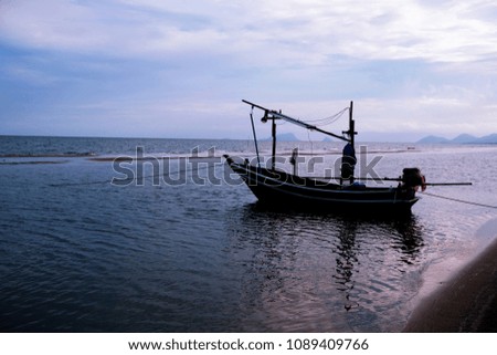 Background of Thai pattern Wooden Fisherman boat is anchored near the beach after back from fishing in the sea. Boat is install the light for fishing at night. Seascape with clear blue sky. Sunset.