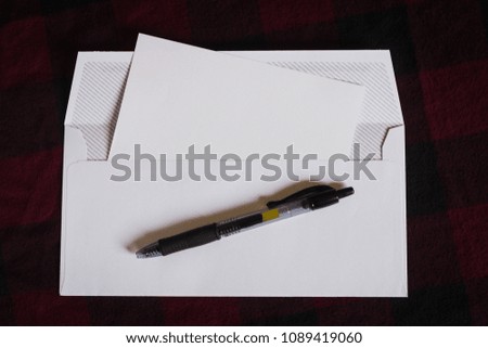 white envelope  with a blank card and a pen 