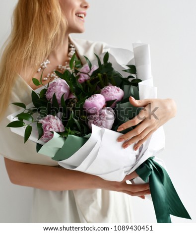 Beautiful woman hold rustic bouquet of pink peonies flowers happy smiling on grey background