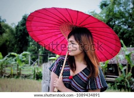 Asian girl wearing traditional Karen coat with red umbrella at Mae Hong Son, North of Thailand