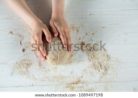Child hands on white background molds, rolls the dough pizza. Dough background. Business roll up. Pizza dough. Happy children.  Wheat flour.