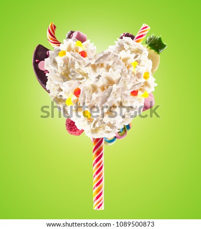Sweet Lolipop in Heart form of whipped cream with sweets, jellies, heart front view. Crazy freakshake food trend. Front view of whipped heart of cream lolly, full of berry and jelly sweets, chocolate