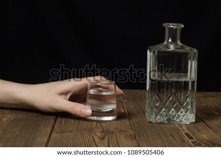 Female hand with a shot of alcohol and a bottle with alcohol, black background