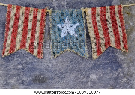 Rustic Memorial Day image of burlap flags painted with stars and stripes on worn steel background. Copy space.