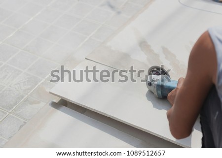 Worker uses stone cutter to cutting fiber cement board. Royalty-Free Stock Photo #1089512657