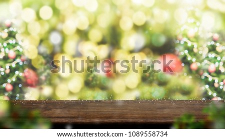 Empty dark brown wood table top with abstract blur christmas tree red decor ball and snow fall background with bokeh light,winter Holiday backdrop,Mock up for display of product.panoramic banner
