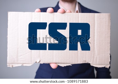 A businessman holds a cardboard with an inscription:CSR