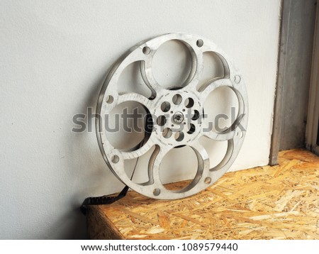 A 16mm film roll sitting on a wooden shelf
