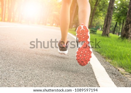 Photo from the back of a young woman Jogging in the park in the morning under warm sunlight