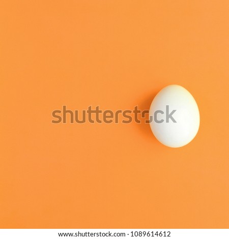 One white easter egg on a bright orange background