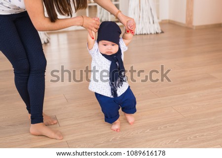 mother holding baby's hands to help him to walk. First step concept