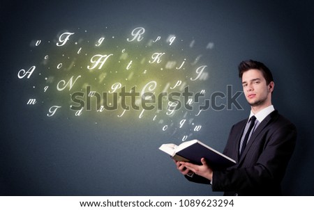 Casual young man holding book with shiny letters flying out of it