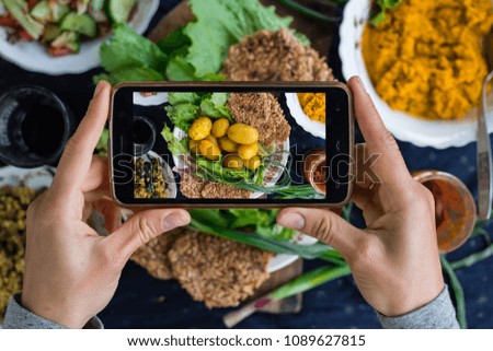 Woman hands take phone photography of food. Smartphone photo of lunch, dinner with backed new potatoes for social media or blogging. Raw vegan vegetarian healthy food