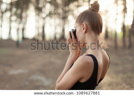 Hipster girl with using vintage photo camera close up, copy space of blank empty mockup, view tourist holding in hands and photograph on device travel on background pine forest