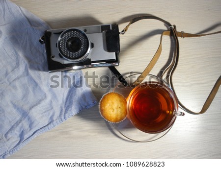 Flat lay. Vintage retro camera. Cupcakes with tea on beige background
