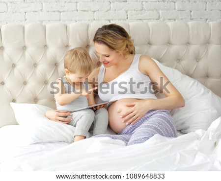 Portrait of a pregnant mother and son with tablet in hand on the
