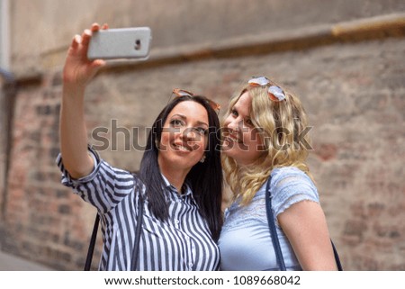 Two young beautiful women making selfie in the old city. Holidays and fun. 